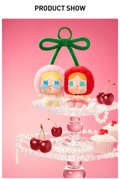 Pop Mart Cry Again Series, love you cherry much. Two plush toys with colorful hair on a decorative stand with cherries and a cupcake against a pink background.