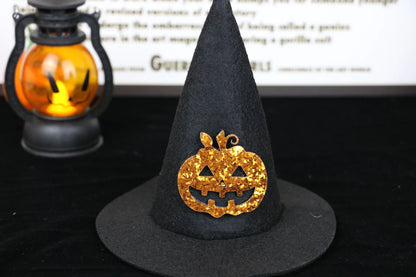 Labubu boots. Black witch hat with gold pumpkin design on a dark background