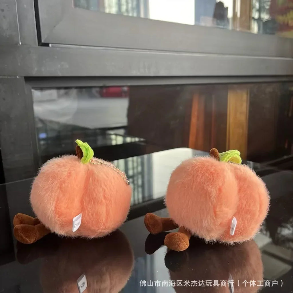 Two plush pumpkin toys on a reflective surface with a blurred background