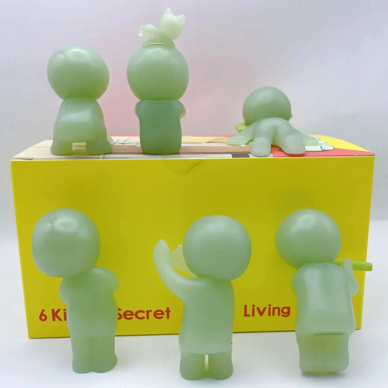 Smiski, living room series. Set of green figurines in front of a yellow box with 'Secret Living' branding.