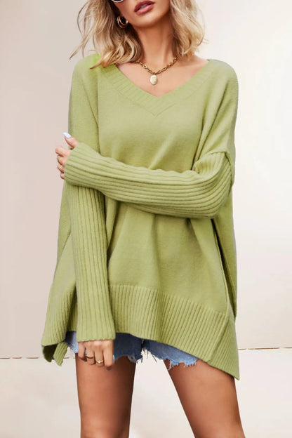 Woman wearing a green sweater and denim shorts against a plain background