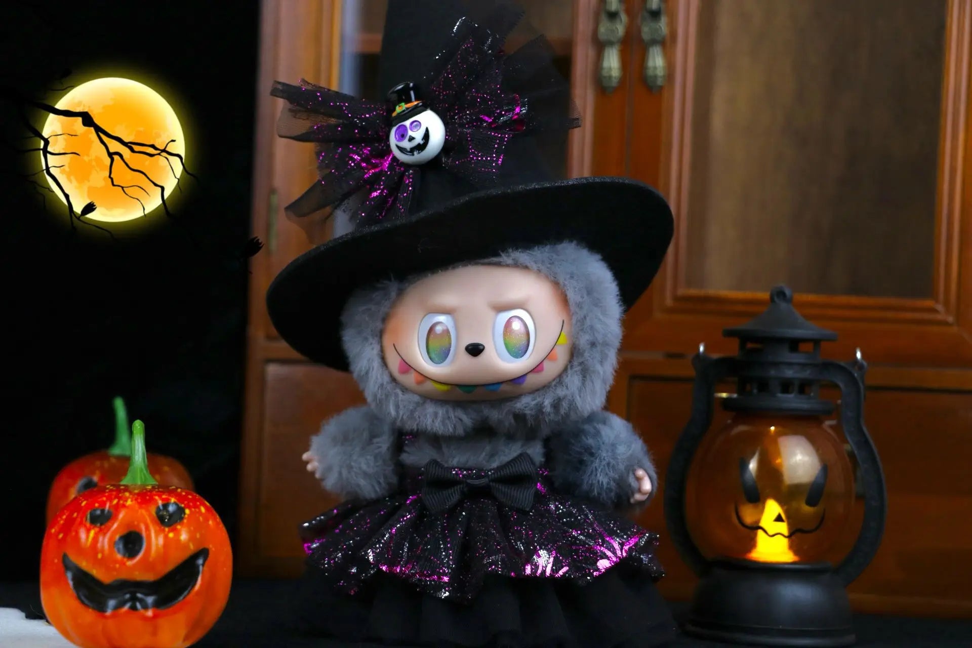 Labubu Halloween dress. Halloween-themed plush toy with a witch hat and pumpkin lanterns in the background.