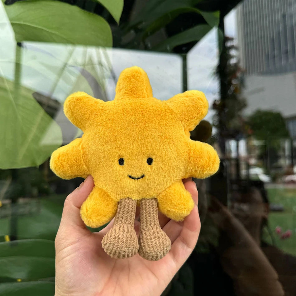 Jellycat. Yellow plush sun toy held in a hand with a blurred outdoor background
