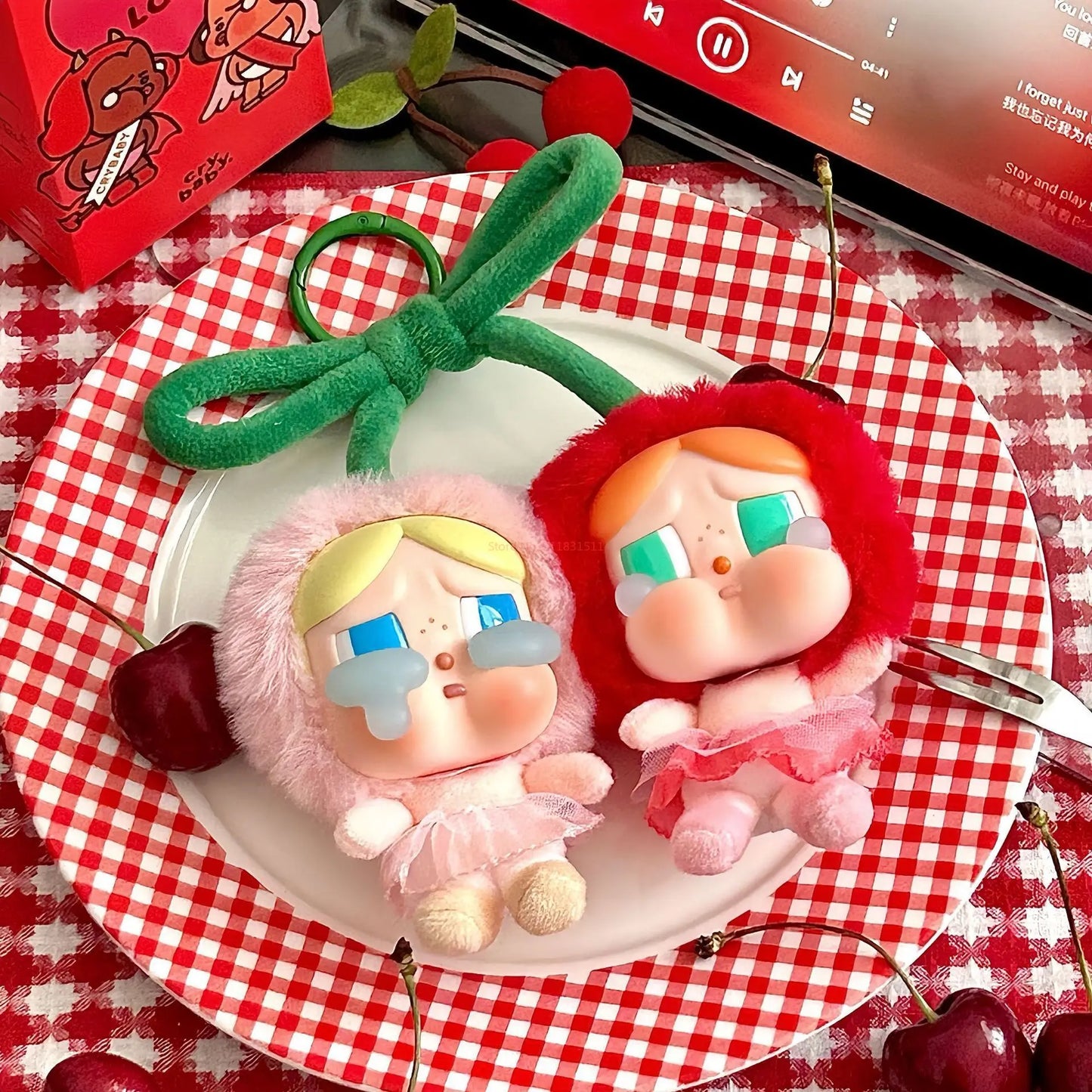 Pop Mart Cry baby, love you cherry much. Two cartoon-style figurines on a plate with cherries and a checkered tablecloth.