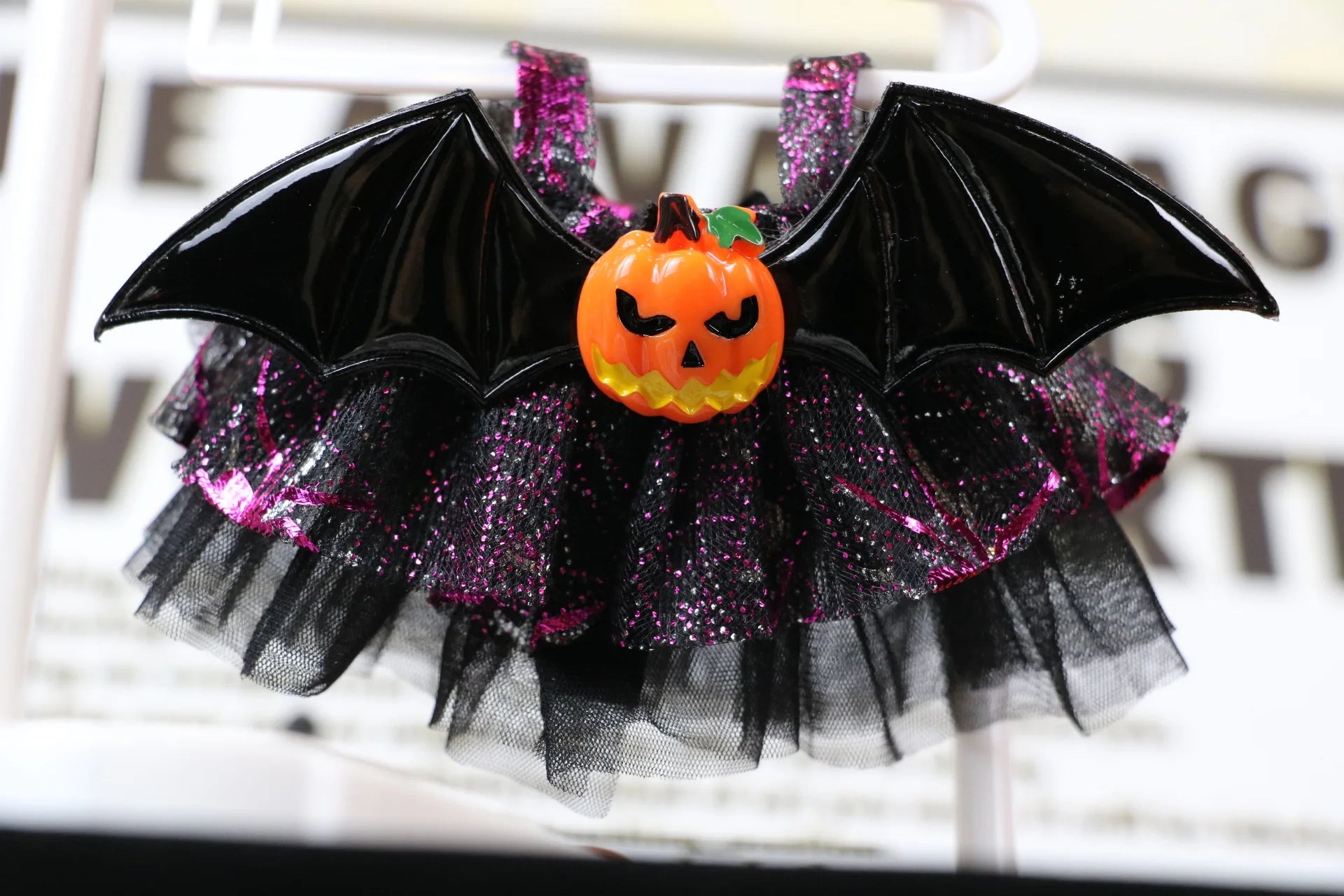Labubu Halloween dress. Halloween-themed decorative item with bat wings, pumpkin, and tulle skirt on a white background