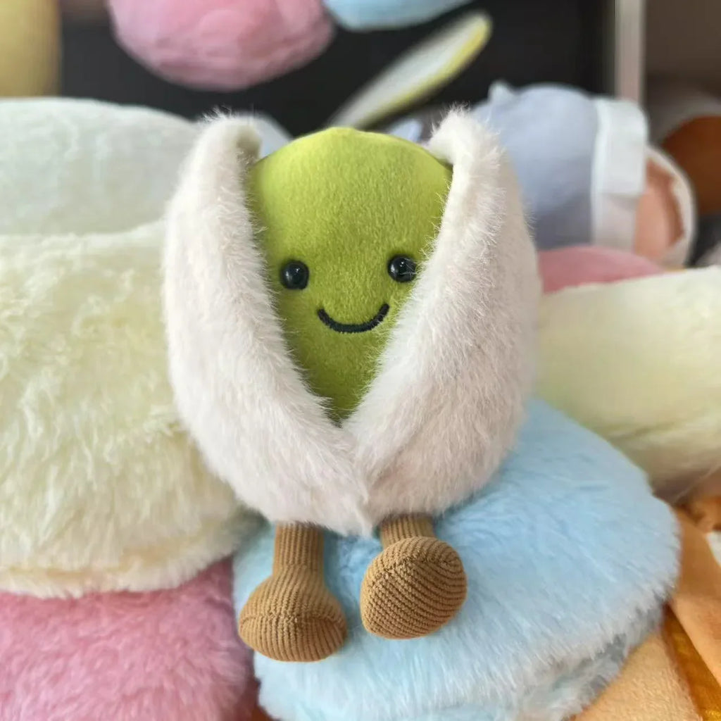  pistachio. Plush toy resembling a green character with a white cape on a colorful background