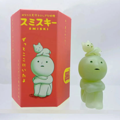 Smiski, living room series. Green Smiski figurine next to its red packaging with Japanese text