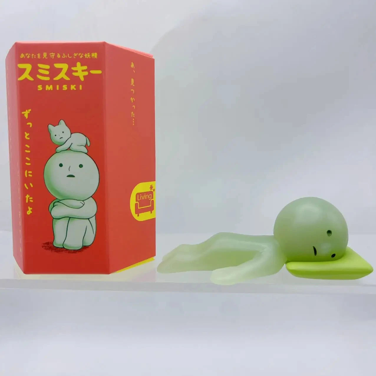 Smiski, living room series. Green plush toy with a red box featuring 'Smiski' branding on a white background