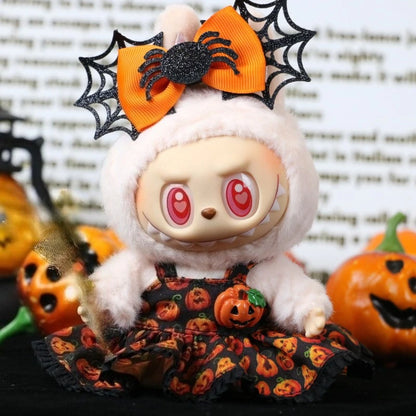 Labubu Halloween dress. Plush toy with Halloween-themed outfit and bow, surrounded by pumpkins.