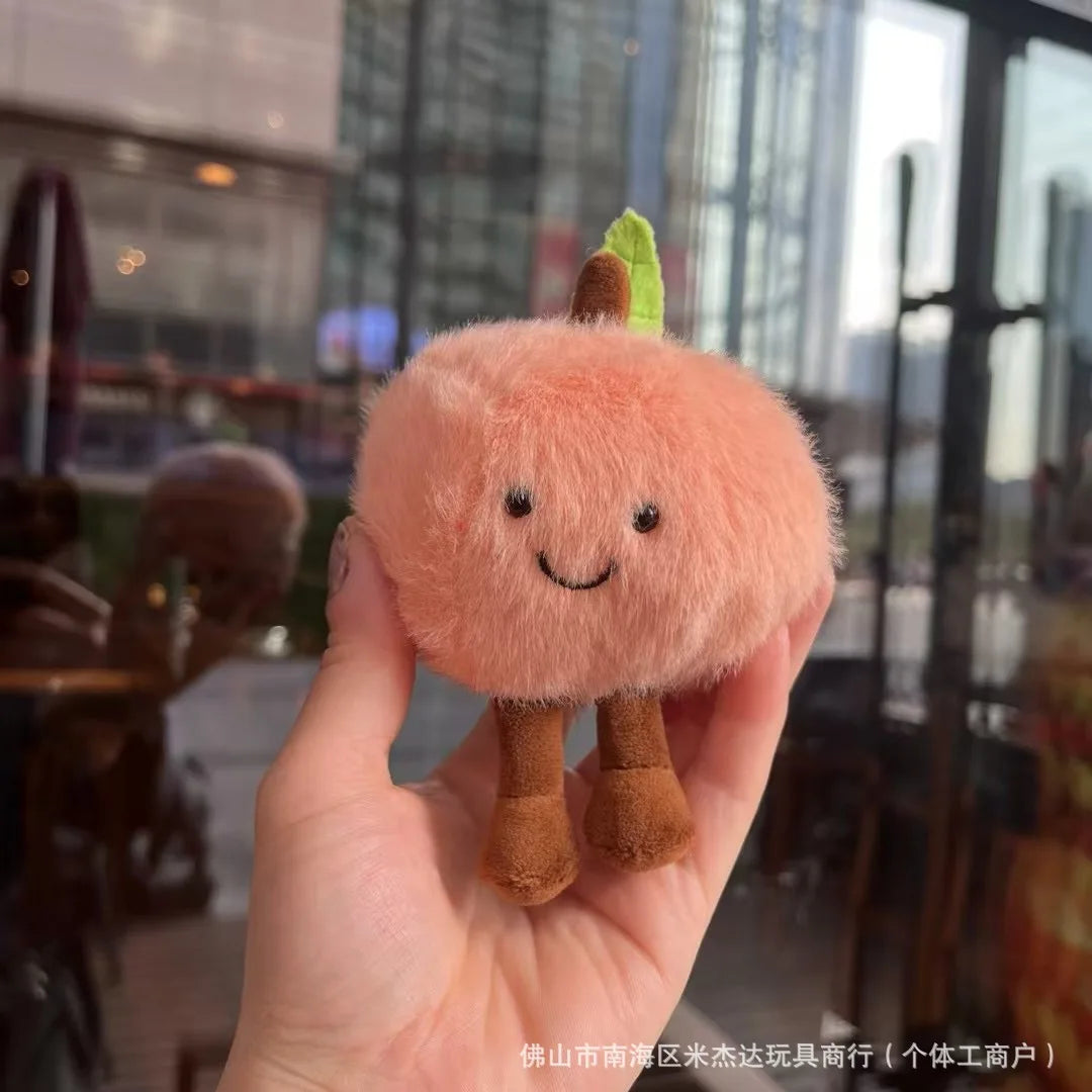  Plush toy resembling a peach held in a hand with a blurred indoor background