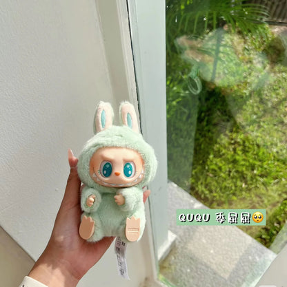 Green plush toy Popmart Labubu have a seat held in a hand with a blurred green outdoor background