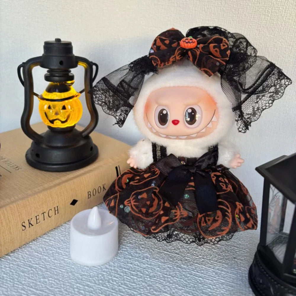 Halloween-themed Labubu toy with black lace and pumpkin patterns, next to a lantern and book.
