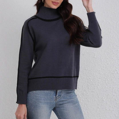 Person wearing a dark blue turtleneck sweater and light blue jeans against a plain background