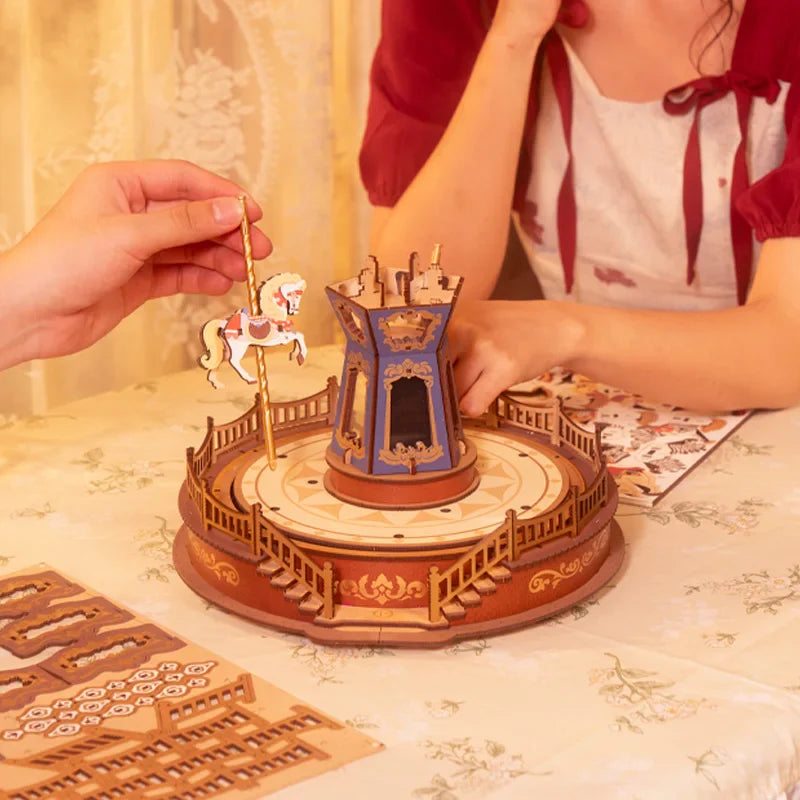 Wooden carousel model with a person interacting with it on a table.