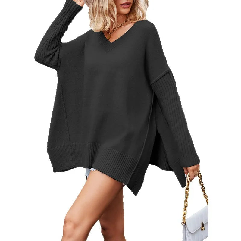 Person wearing a black oversized sweater holding a white handbag with gold chain.