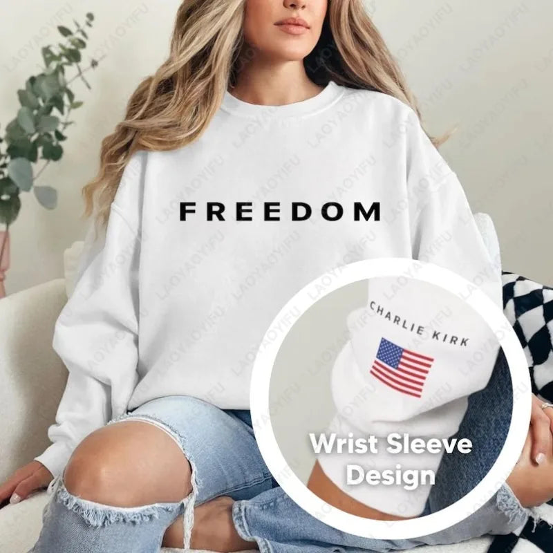 Person wearing a white sweatshirt with 'FREEDOM' text, holding a wrist sleeve with 'CHARLIE KIRK' branding.