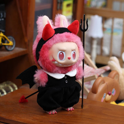 Labubu figure of a character in a pink devil costume with red horns and tail on a wooden surface.