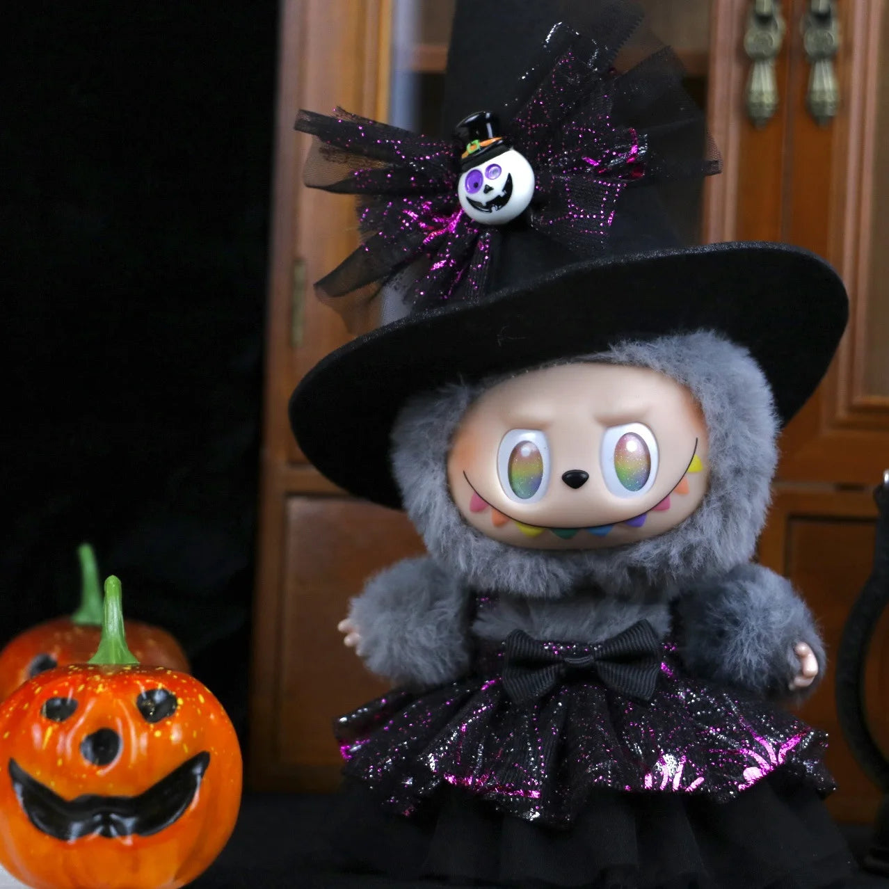 Labubu Halloween dress. Halloween-themed plush toy with black hat and skirt next to a pumpkin.
