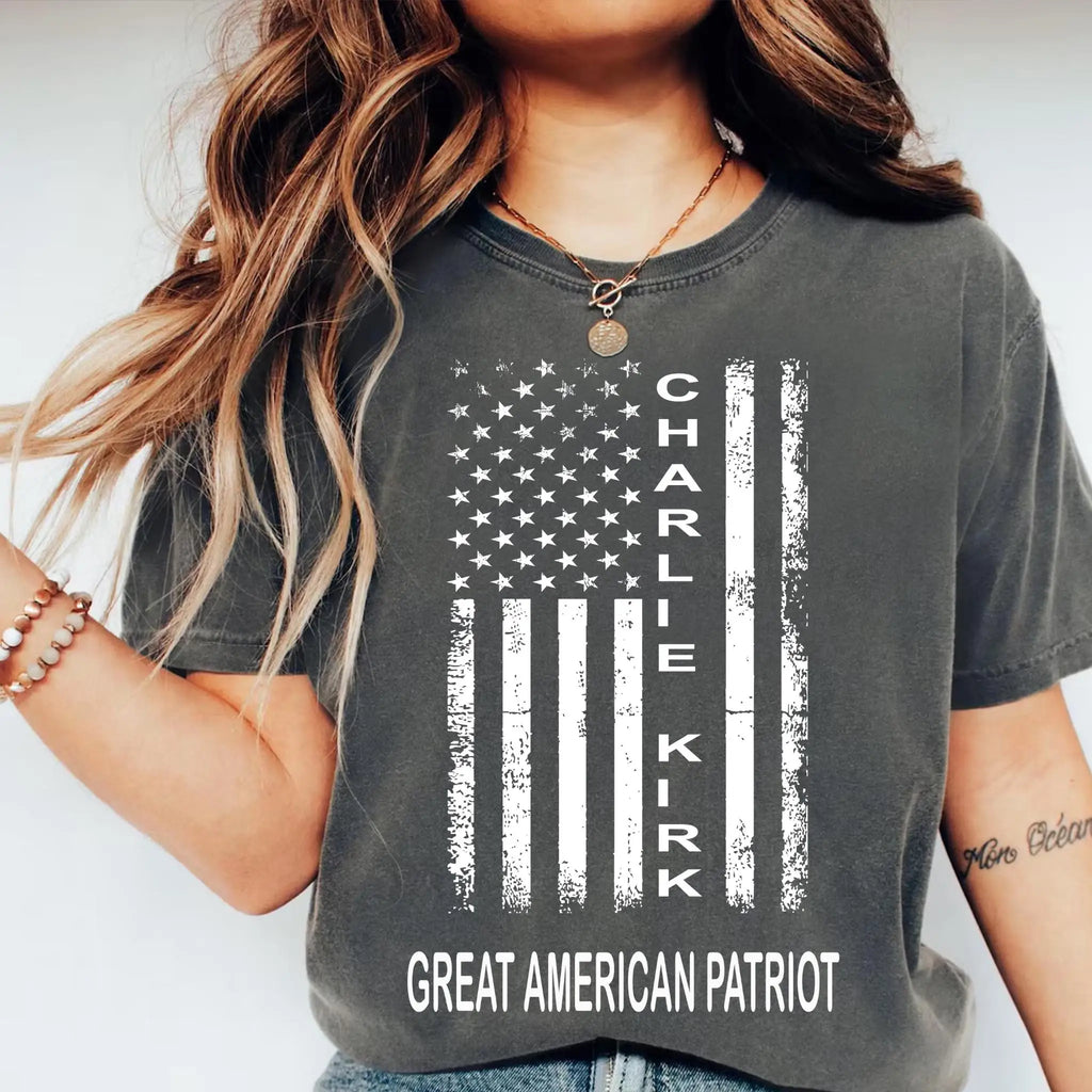 Person wearing a gray t-shirt with an American flag design and Charlie Kirk written on it.