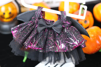 Labubu Halloween dress. Black and pink glittery skirt with a bow on a hanger against a Halloween-themed background.