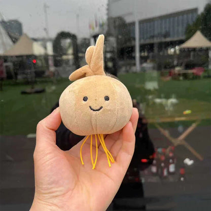 Jellycat. Plush toy shaped like a smiling onion held in a hand with an outdoor background