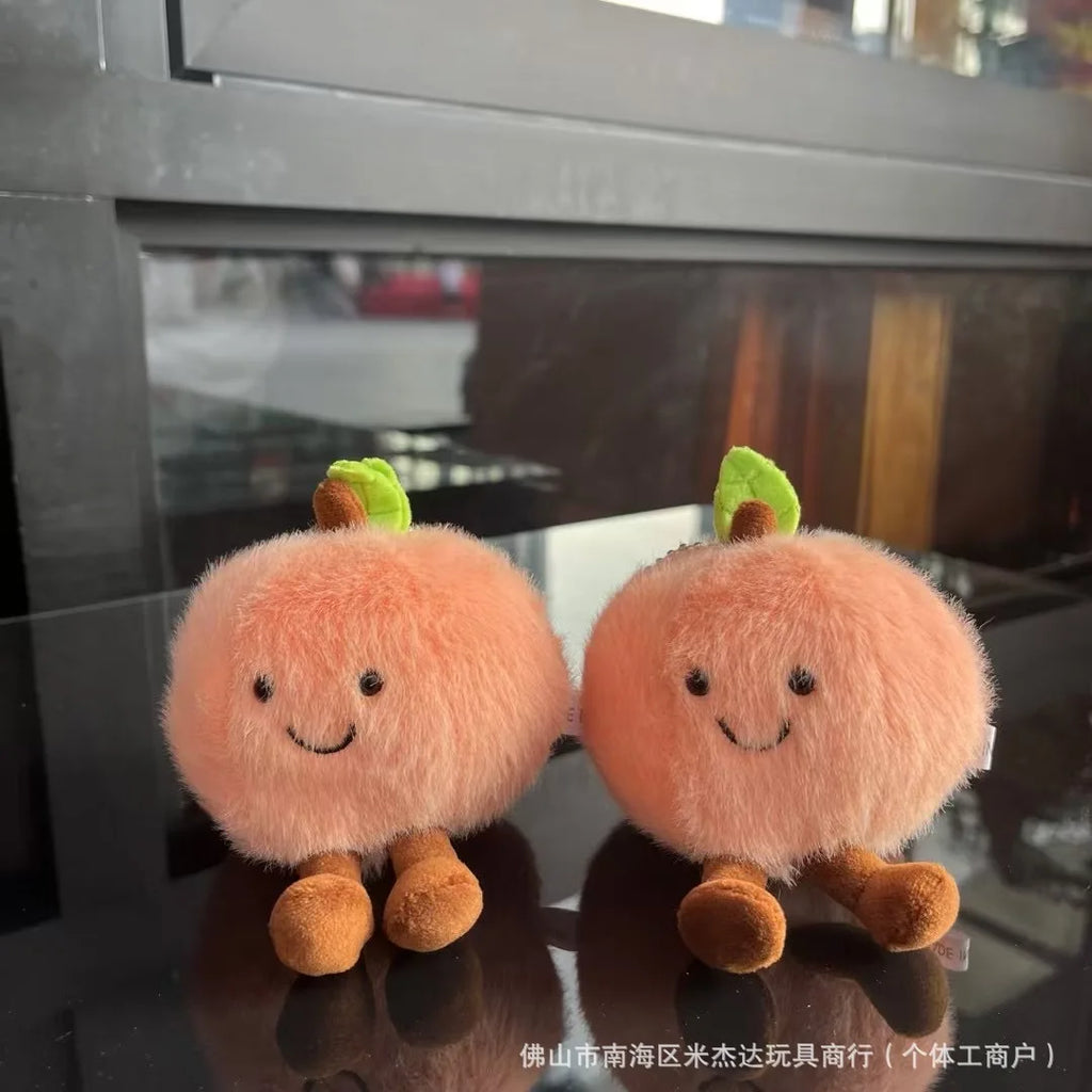 Two plush peach toys with smiling faces on a reflective surface.