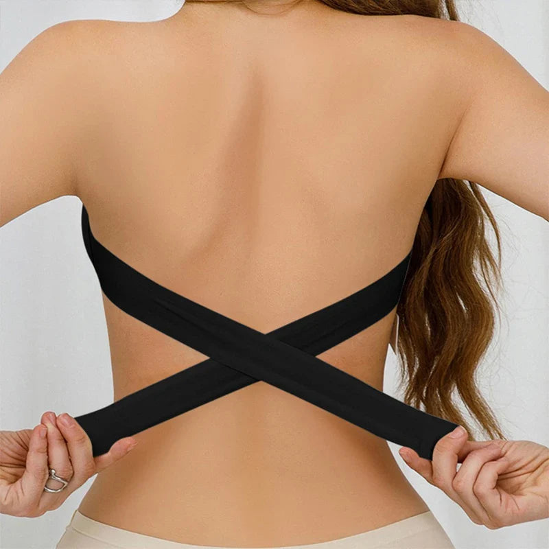Person wearing a black strappy top with a plain background