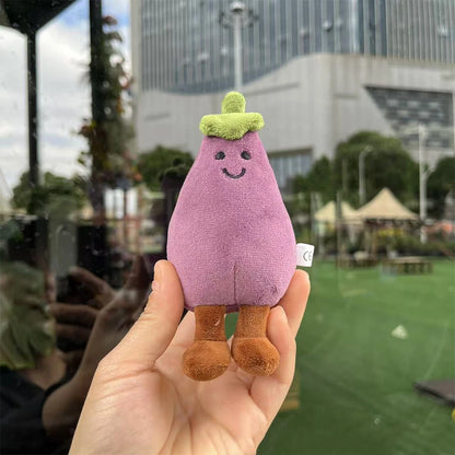 Jellycat. Plush toy resembling an eggplant held in a hand with a cityscape background