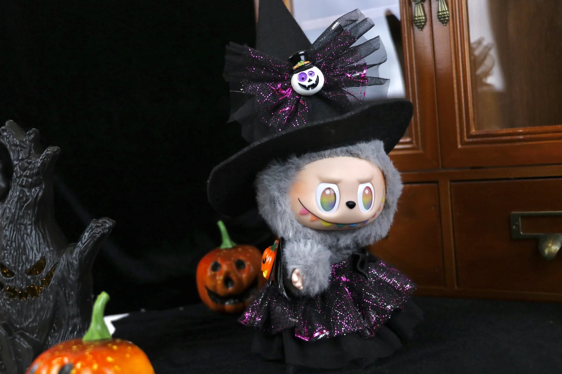 Labubu in a witch costume with Halloween decorations
