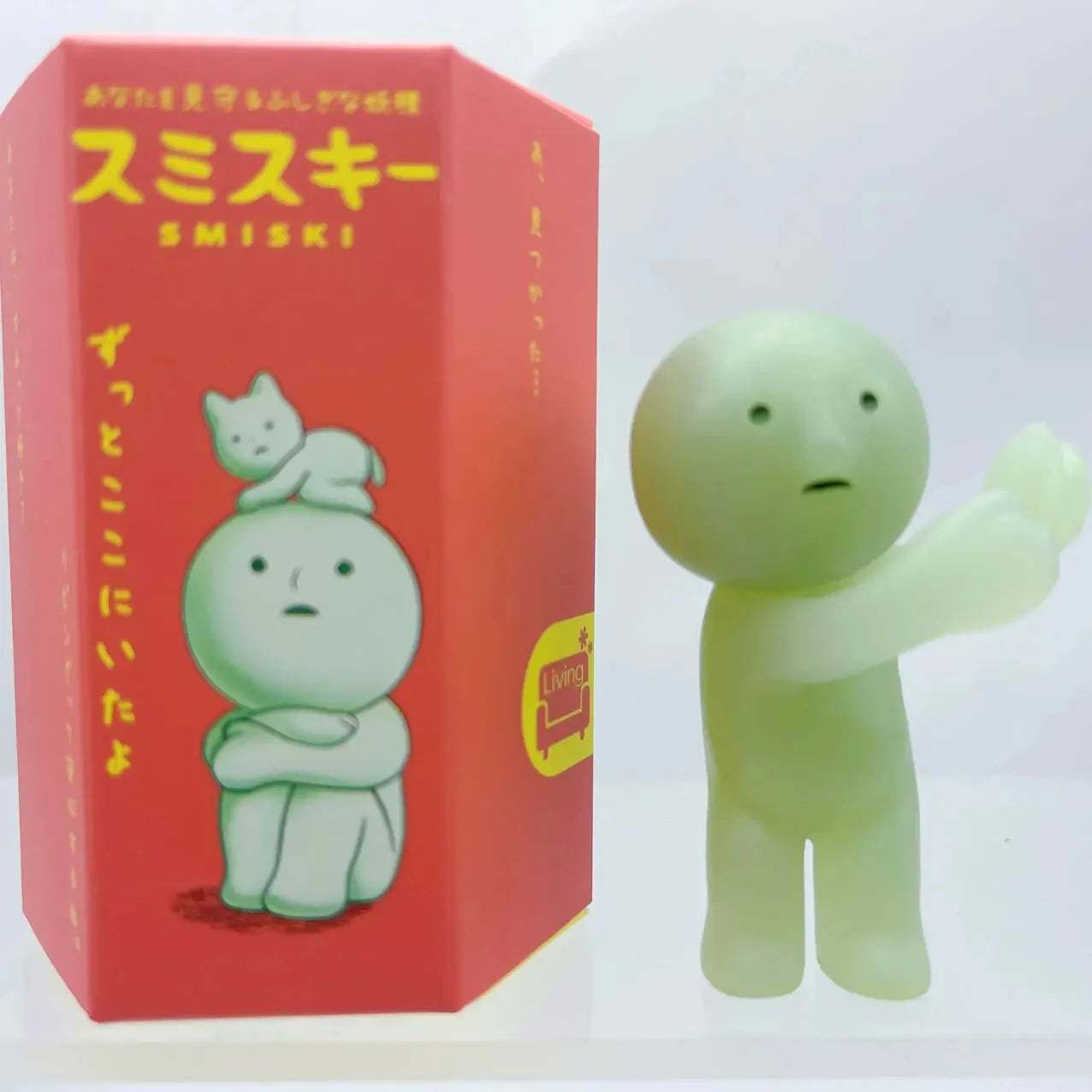 Smiski, living room series. Green figurine next to its red box with cartoon design and text