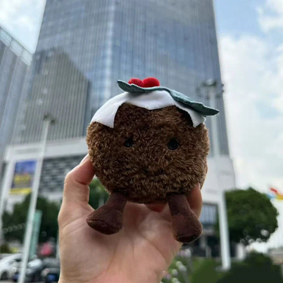 Jellycat. Plush toy resembling a brownie with a white topping held in front of a cityscape.