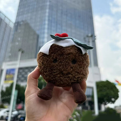 Jellycat. Plush toy resembling a brownie with a white topping held in front of a cityscape.