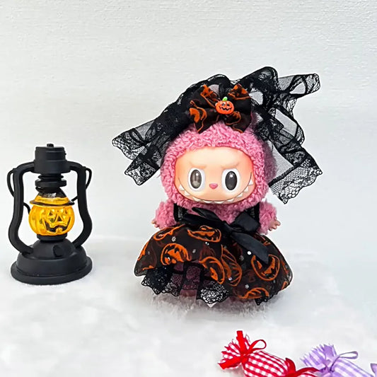 Labubu. Halloween-themed doll with pink hair and black lace headband next to a lantern on a white background