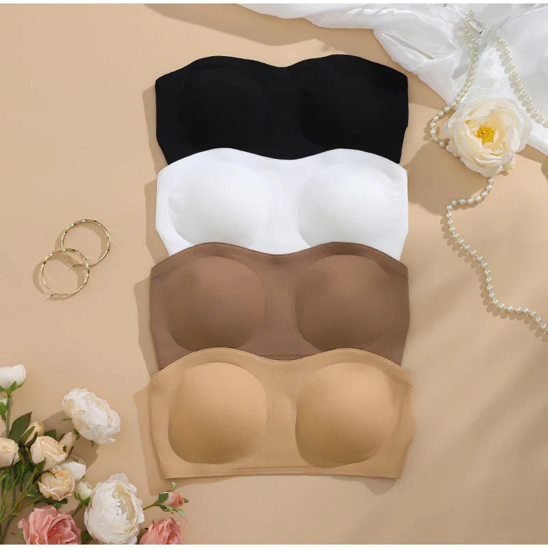 Set of black, white, and brown strapless bras on a beige surface with flowers and jewelry.
