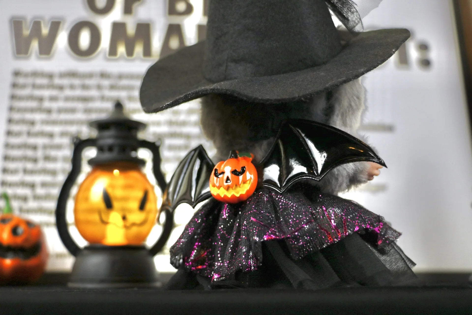 Labubu Halloween dress. Halloween-themed decoration with a witch hat, bat wings, and pumpkin on a blurred background.