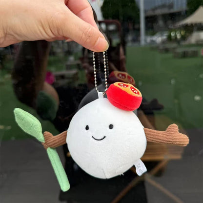 Mozzarella. Plush keychain shaped like a white dumpling with a red top held by a hand outdoors.
