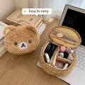 Bear-shaped makeup bag with cosmetic items on a desk next to a laptop