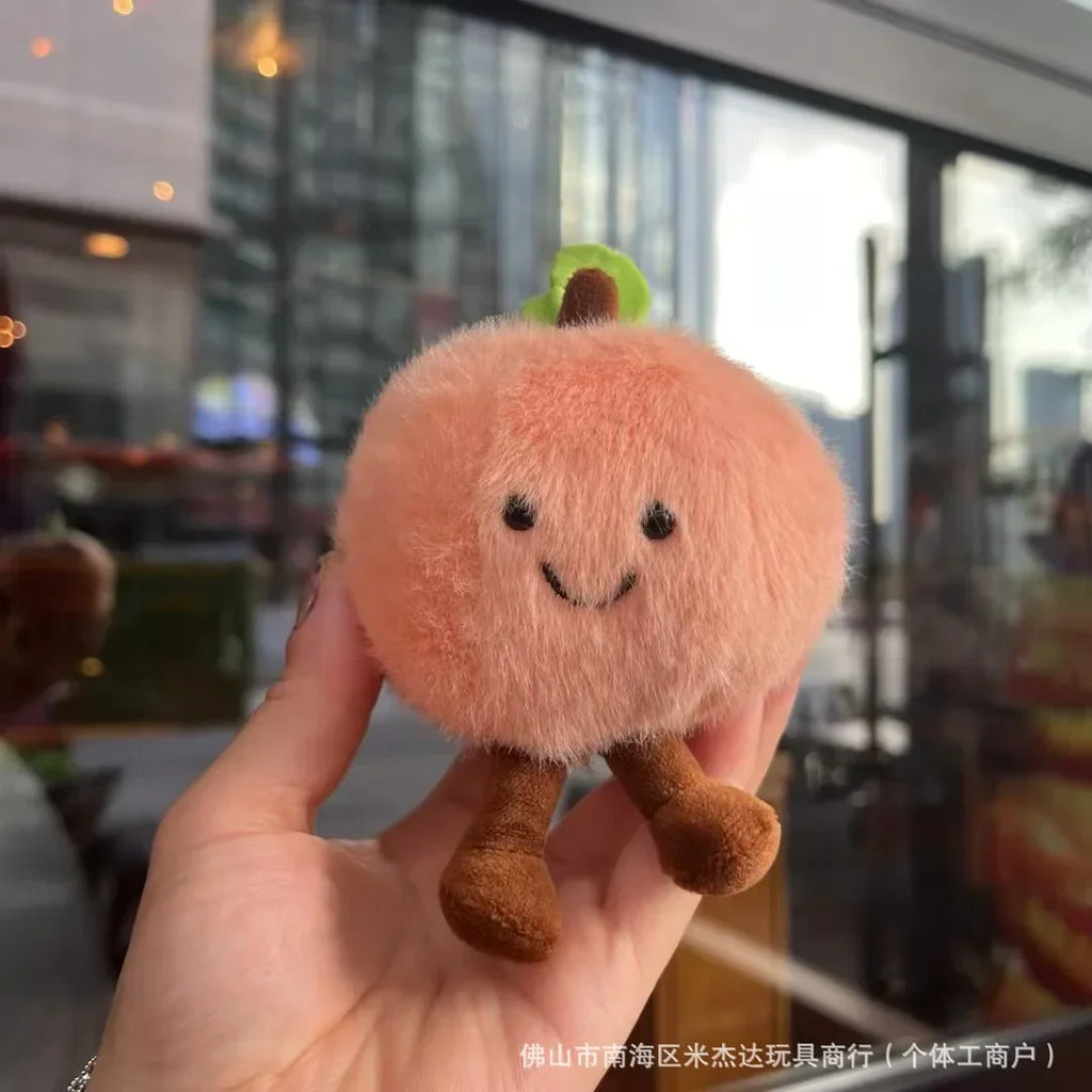 Plush toy resembling a peach held in a hand with a blurred indoor background