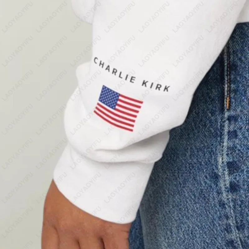 White sleeve with American flag and 'Charlie Kirk' text on a person wearing blue jeans.