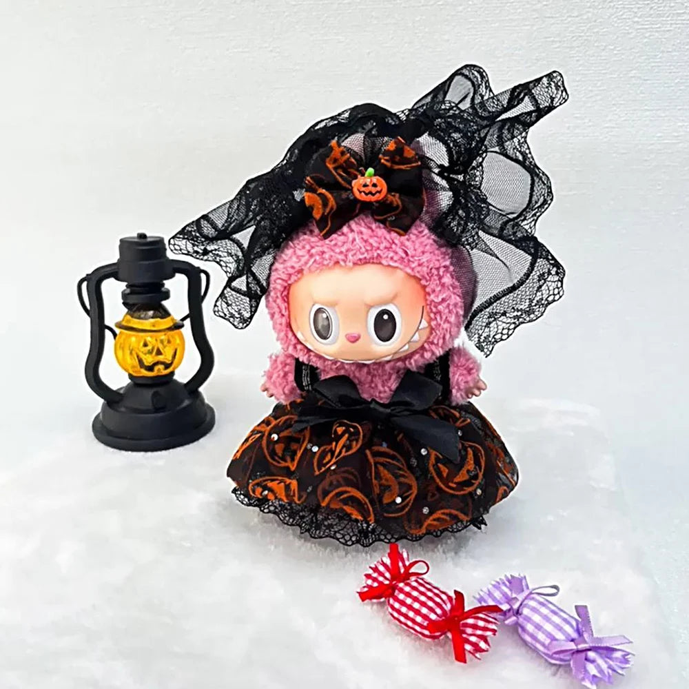 Halloween-themed Labubu with pink hair, black veil, and orange skirt, next to a lantern and candy on a white background.